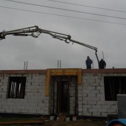 PIOTR ŚLADEWSKI ISO-GLAZ - Budowa domu z betonu komórkowego: pracownicy obsługują pompę do wylewania betonu na strop, widoczne zbrojenia i szalunki okienne.