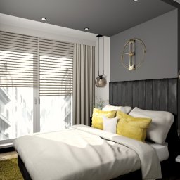 Befart Beata Nowacka - Sypialnia z łóżkiem z czarnym zagłówkiem, żółtymi poduszkami i okrągłym, złotym zegarem na szarej ścianie, oświetlona wiszącymi lampami z kulistymi kloszami.