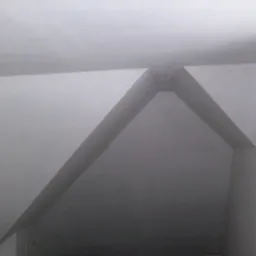 Szare wnętrze z widoczną konstrukcją sufitu podwieszanego, tworzącą geometryczny wzór z ukośnych linii i kątów prostych.