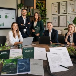 EcoPan - Zespół pięciu profesjonalistów w nowoczesnym biurze, z ekranem wyświetlającym dashboard ESG i certyfikatami ISO. Na stole firmowe broszury o ESG, finansach i dotacjach.