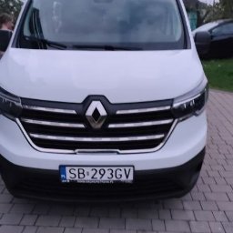 MB-Trans - Biały bus Renault z chromowanym grillem i polską tablicą rejestracyjną SB 293GV, zaparkowany na szarej kostce brukowej przed budynkiem.