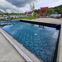 Green Design - Nowoczesny basen z błękitnymi mozaikowymi płytkami, otoczony kamiennym ogrodem z zieloną trawą i czerwonym japońskim łukiem Torii. W tle domy i drzewa.
