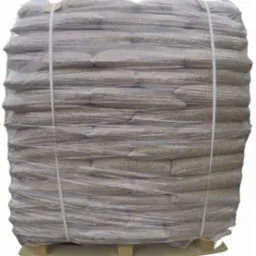 Paleta z workami agropelletu, owinięta folią, zabezpieczona taśmami. Widoczne detale struktury pelletu przez przezroczystą folię. Ujęcie z bliska, na jasnym tle.