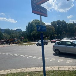 Hive Tax - Skrzyżowanie ulic Towarowej i Grzybowskiej w Mirowie, z widocznymi znakami drogowymi, znakiem strefy płatnego parkowania, tramwajem, samochodami i budynkami w tle.