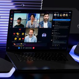 Slash Dot Filip Radomski - Otwarty laptop na ciemnym tle z neonowymi niebieskimi akcentami, wyświetlający wideokonferencję z czterema uczestnikami i aktywnym panelem czatu. Futurystyczna estetyka.