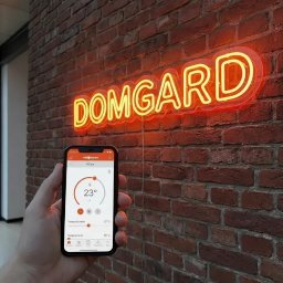 Domgard - Instalacje Optymalne - Ręka trzyma smartfon z aplikacją ViCare Viessmann, wyświetlającą ustawienie temperatury 23°C, na tle ceglanej ściany z pomarańczowym neonem 'DOMGARD'.