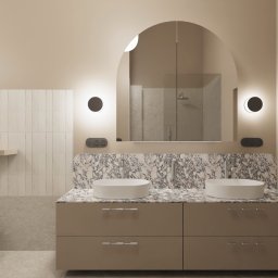 FOGU.studio projektowe wnętrz Paola Major - Elegancka łazienka z beżowymi ścianami, podwójną umywalką na marmurowym blacie, lustrem w kształcie łuku i dekoracyjnymi kinkietami w kształcie półksiężyca. Białe pionowe płytki i wolnostojąca wanna.