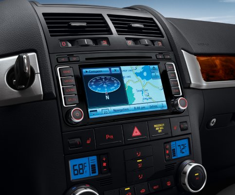 Wnętrze samochodu Volkswagen Touareg z systemem nawigacji RNS 510 z 2013 roku z wyświetlaczem LED, widoczny panel klimatyzacji, przyciski funkcyjne i drewniane wykończenie.