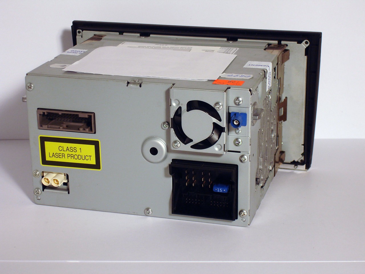 Tył radia samochodowego Audi RNS-E z widocznymi złączami, wentylatorem i naklejką ostrzegawczą lasera.