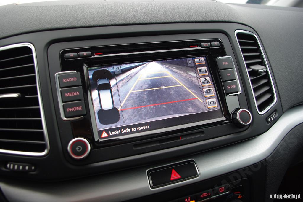 Wnętrze samochodu z wbudowanym systemem nawigacji RNS 510, wyświetlającym obraz z kamery cofania z widocznymi liniami pomocniczymi.