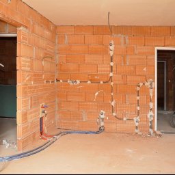 MC Electro Service - Rozprowadzona instalacja elektryczna w szarych peszlach i hydrauliczna w rurach PEX na ścianach z pustaków ceramicznych w pomieszczeniu w Gardeji.