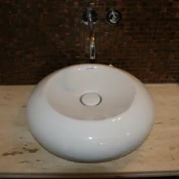 Biała, okrągła umywalka nablatowa marki Duravit na blacie z trawertynu, z mozaiką w odcieniach brązu na ścianie w tle i chromowaną armaturą.