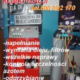 Stanowisko do serwisu klimatyzacji samochodowej z czerwonym urządzeniem diagnostycznym, butlą z gazem i plakatami reklamowymi w tle.