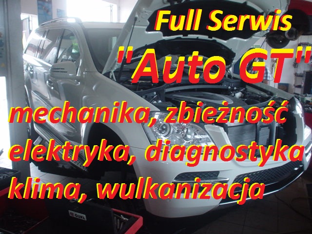 Biały samochód z otwartą maską w warsztacie, widoczne narzędzia i reklama usług warsztatu z tekstem: Full Serwis Auto GT mechanika, zbieżność, elektryka, diagnostyka, klima, wulkanizacja.