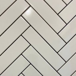 Poznań Remonty - Wykończenia Wnętrz KS BUD - Błyszczące, białe płytki ceramiczne ułożone w jodełkę z ciemnymi fugami, tworzące nowoczesną, geometryczną powierzchnię ściany lub podłogi.