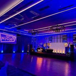 Gremium - Realizacja Techniczna i Studio Nagrań - Elegancka sala eventowa z intensywnym niebiesko-fioletowym podświetleniem, sceną z napisem 'Let's Dance', statuetkami Oscara i ekranem 'Schibsted Tech Polska Oscar NIGHT'. Widoczne stoły...