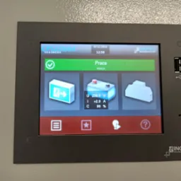 Ekran dotykowy panelu sterowania systemu, wyświetlający status 'Praca' wraz z parametrami napięcia, prądu i procentu naładowania, obudowa panelu marki INOTEC.