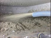 Aplikacja granulatu izolacyjnego na stropodach za pomocą węża pneumatycznego. Widoczna warstwa izolacji i dysza rozpylająca materiał.