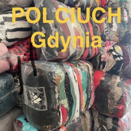 POLCIUCH Hurtownia Odzieży Używanej - Zafoliowane, sprasowane paczki z różnorodnymi ubraniami, ułożone w stos, z widocznym logo Adidas na jednej. Na zdjęciu żółty napis 'POLCIUCH Gdynia'.