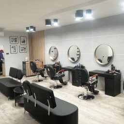 DARPOL Dariusz Sabela wykończenia wnętrz - Nowoczesny barbershop z trzema stanowiskami, czarnymi fotelami fryzjerskimi, okrągłymi lustrami w drewnianych ramach, szarymi ścianami i jasną podłogą imitującą drewno.
