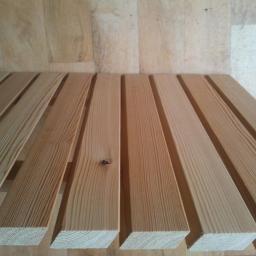 Centrum Drzewne Lucjan Huczek - Jasne, świerkowe deski ułożone równolegle, widoczne słoje drewna i drobne sęki, w tle drewniana podłoga.