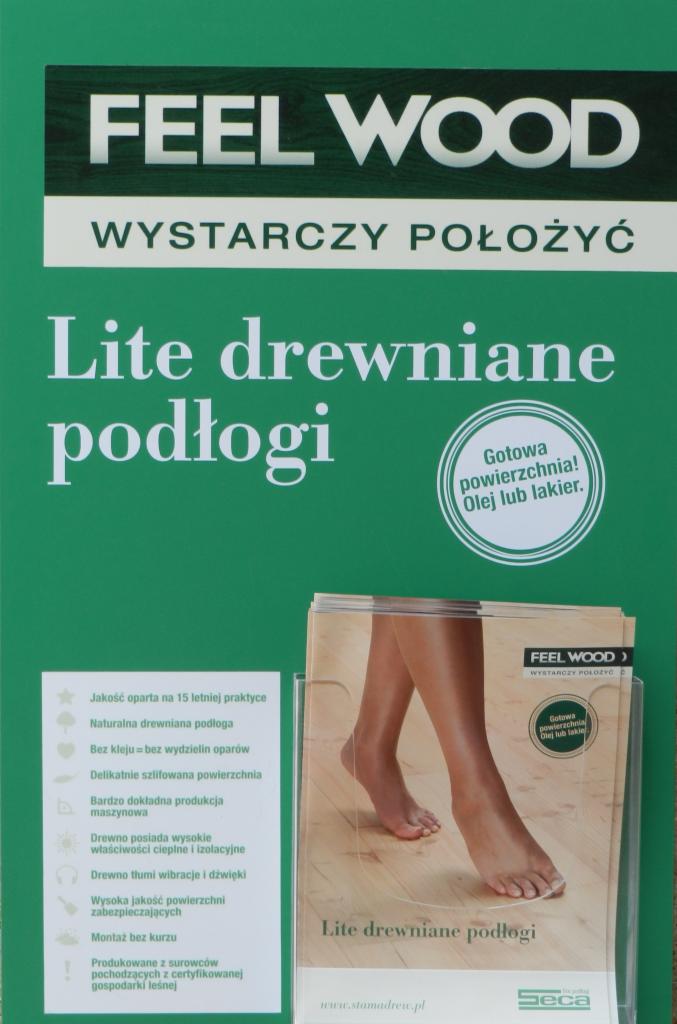 Reklama litej drewnianej podłogi marki Feel Wood, z hasłem 'Wystarczy położyć'. Ulotka prezentuje naturalną podłogę z certyfikowanego drewna.