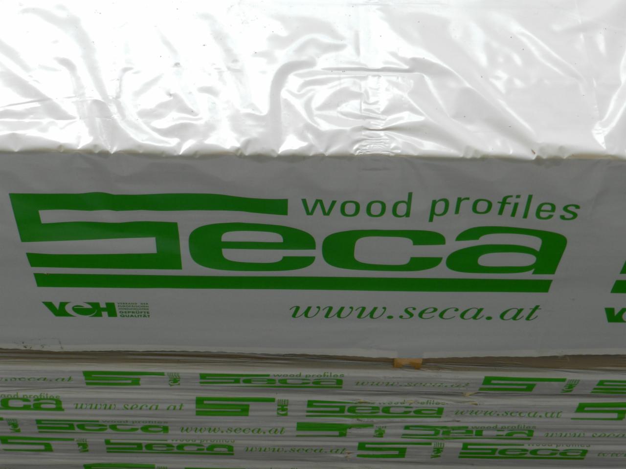 Stos tarcicy budowlanej marki Seca, zapakowanej w folię. Widoczne logo i adres strony internetowej. Ujęcie z bliska, skupione na opakowaniu.