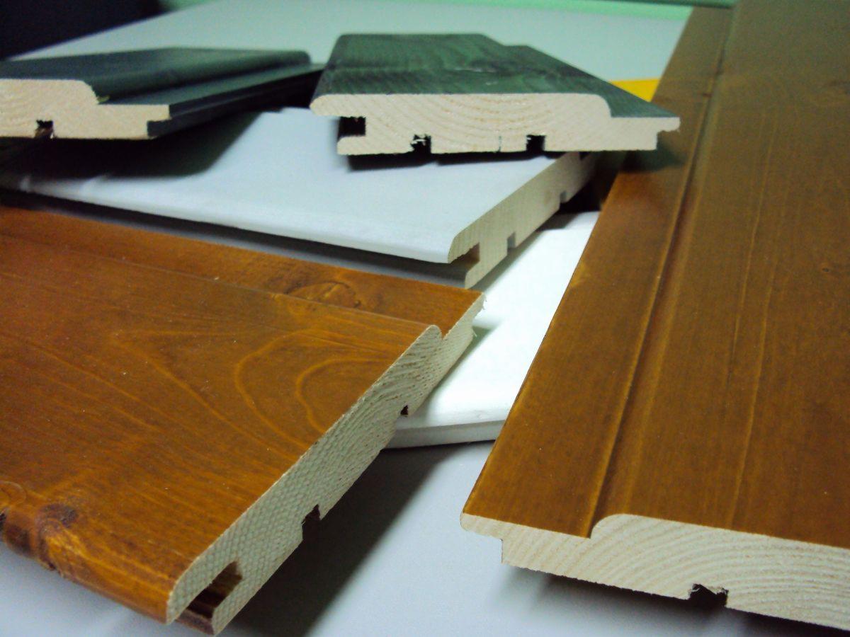 Przekrój bejcowanej deski podłogowej z widocznym profilem pióro-wpust. Różne kolory bejcy, od ciemnych do jasnych odcieni brązu. Detal wykończenia.