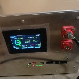 SzychTech Energy - Metalowa obudowa systemu magazynowania energii z cyfrowym wyświetlaczem pokazującym parametry pracy i czerwonymi złączami kablowymi, w Łomży.