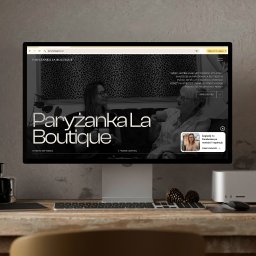 EnterSpace - Monitor wyświetlający stronę internetową butiku odzieżowego 'Paryżanka La Boutique' z Pucka, prezentującą ofertę ubrań dla kobiet. Na drewnianym biurku klawiatura, mysz i szyszki.