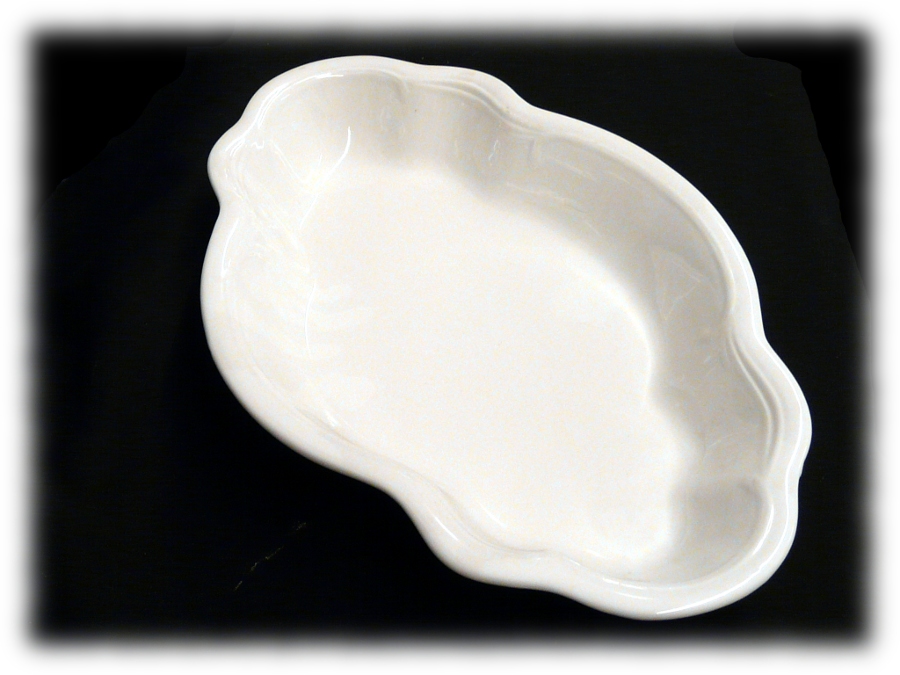 Pusta, biała, ceramiczna patera o nieregularnym, falistym kształcie, ustawiona na czarnym tle.