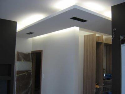 Nowoczesne wnętrze z podwieszanym sufitem, oświetleniem LED i czarnymi elementami wykończeniowymi; drzwi zabezpieczone folią ochronną w tle.