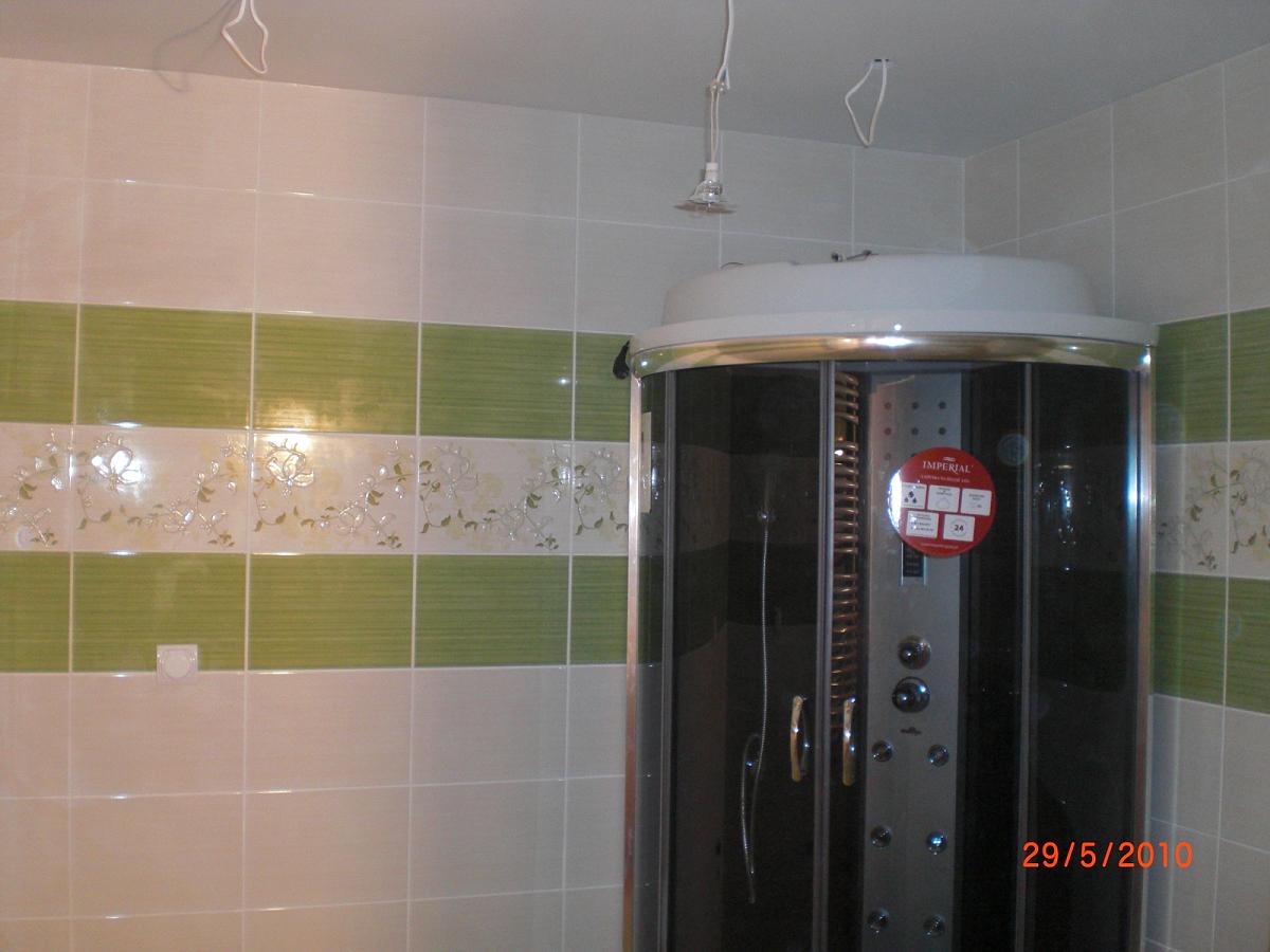 Kabina prysznicowa z hydromasażem w łazience wyłożonej białymi i zielonymi płytkami z motywem kwiatowym, widok z bliska.