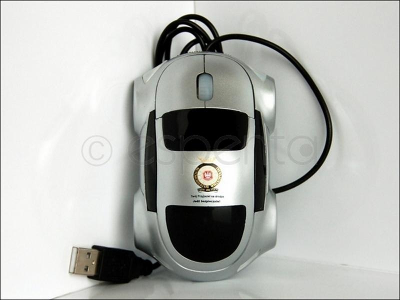 Srebrna mysz komputerowa w kształcie samochodu z naklejką promującą bezpieczeństwo na drodze, leżąca na białym tle.