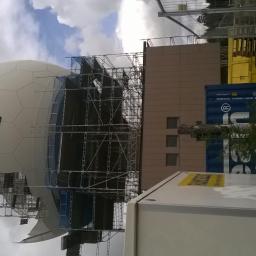 Artel Electric - Konstrukcja sferyczna w trakcie montażu, otoczona rusztowaniami, z widocznymi elementami budynku i kontenerami w tle.