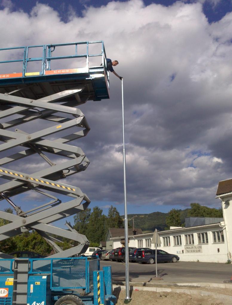 Montaż pionowego uziomu instalacji odgromowej we Wrocławiu z wykorzystaniem podnośnika nożycowego, widoczne budynki w tle.