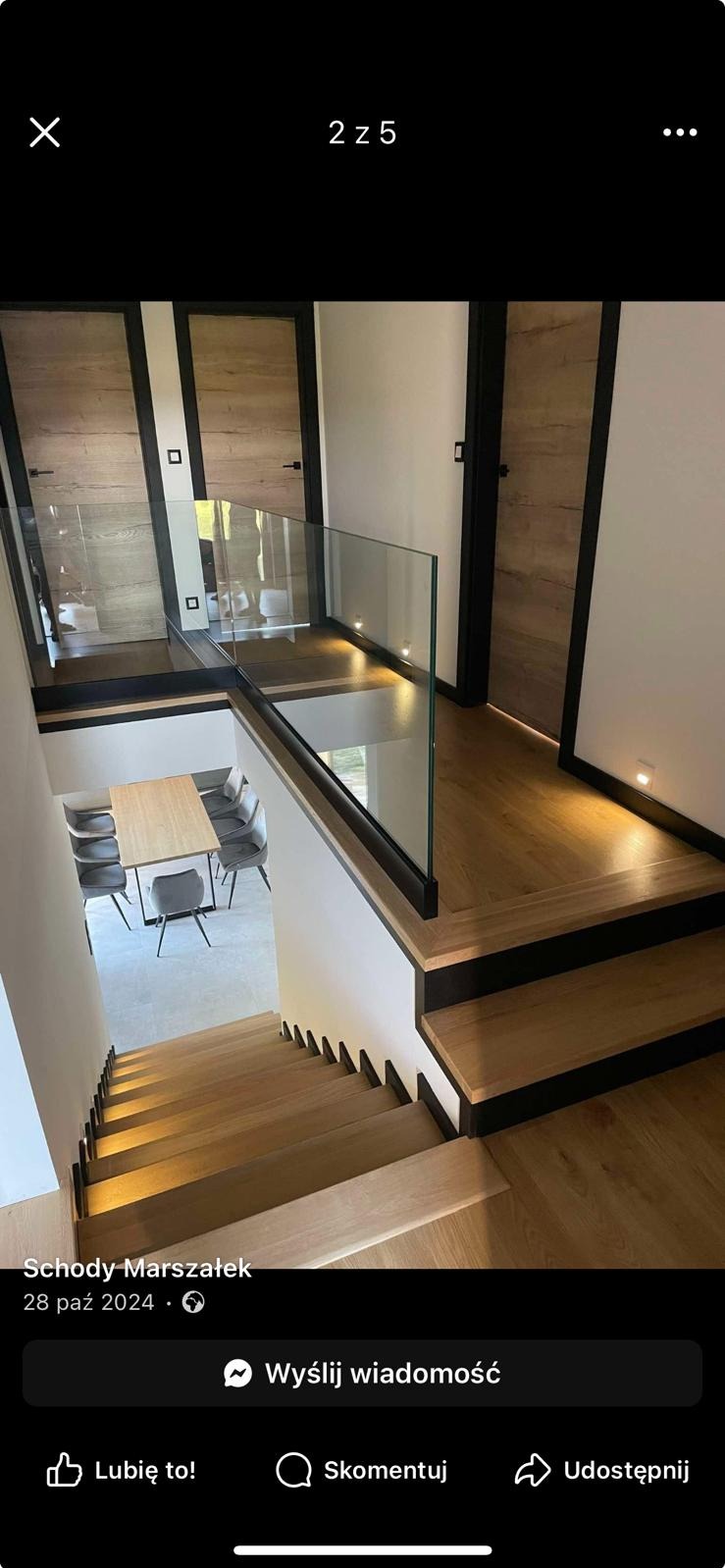 Nowoczesne schody drewniane z balustradą szklaną i czarnymi elementami wykończeniowymi. Widok z góry na dół, w tle stół i krzesła w jadalni.