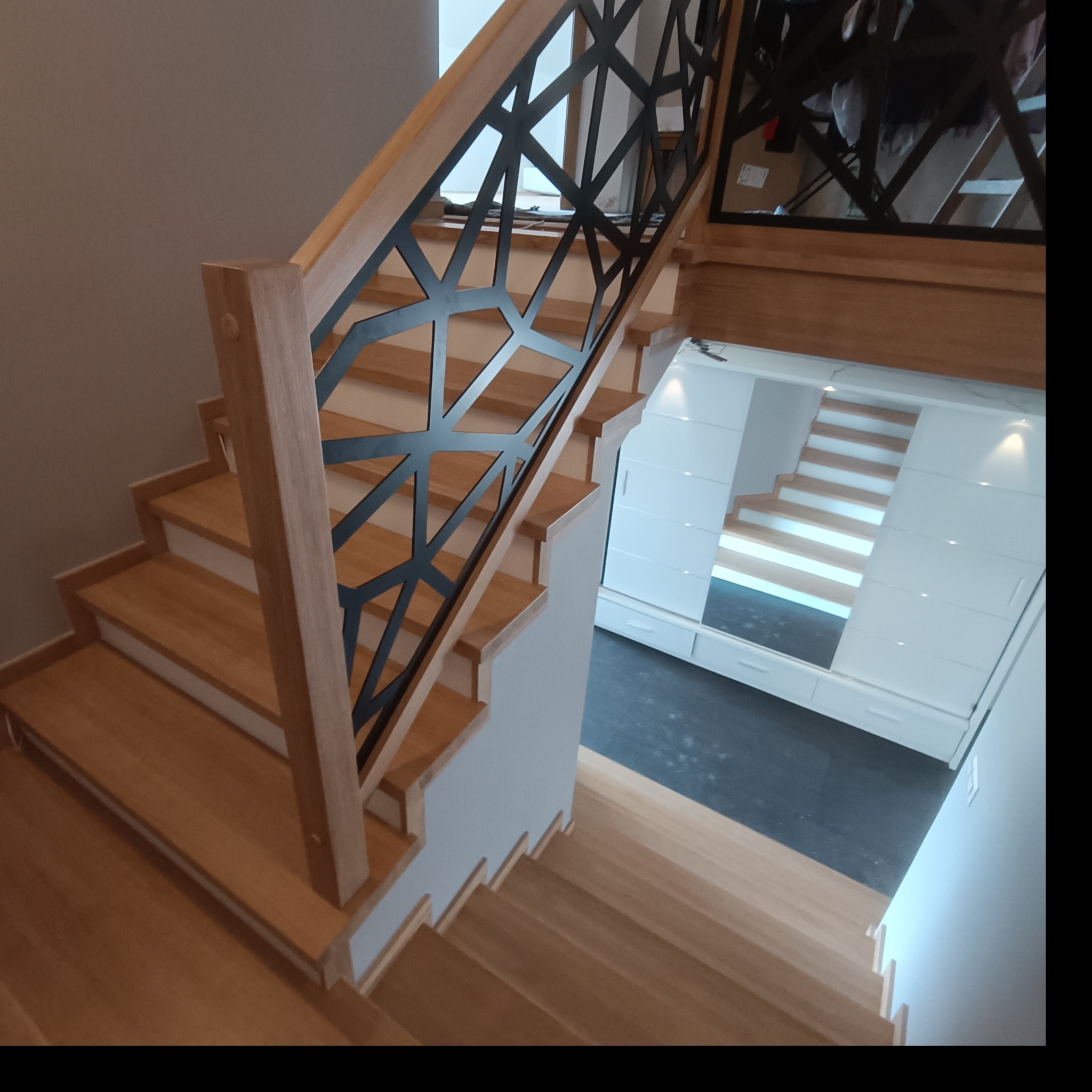 Nowoczesne schody z jasnego drewna z czarną, geometryczną balustradą w Bystrej. Widok z góry, ukazujący detale wykończenia i minimalistyczny design.