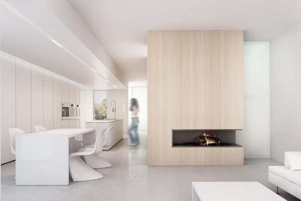 Minimalistyczne wnętrze: biała kuchnia z jadalnią, drewniany kominek z paleniskiem i rozmyta postać kobiety w tle, całość utrzymana w jasnej tonacji.
