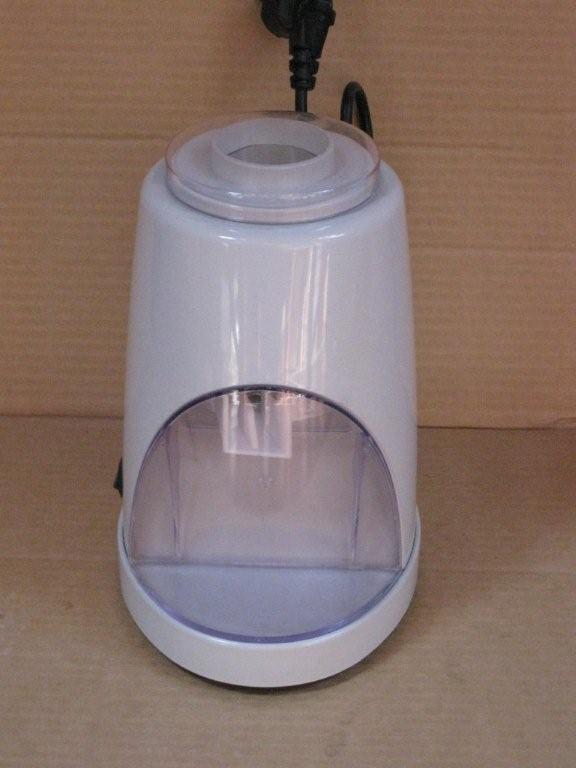 Biała, domowa kruszarka do lodu z przezroczystym zbiornikiem na lód, ustawiona na blacie, z widocznym kablem zasilającym.