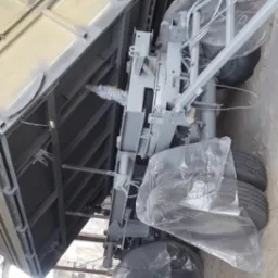 Widok podwozia samochodu ciężarowego po piaskowaniu i malowaniu na szaro, z elementami zabezpieczonymi folią, widoczne opony i elementy konstrukcyjne.