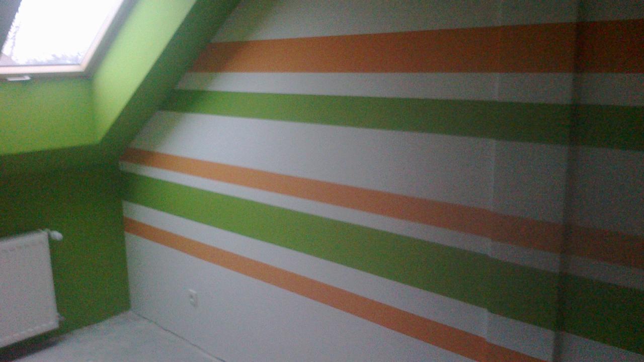 Pokój na poddaszu po malowaniu ścian w poziome pasy: zielone, pomarańczowe i białe. Widoczny grzejnik i okno dachowe.