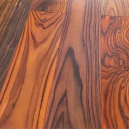 Zbliżenie na parkiet z egzotycznego drewna o wyraźnym, falistym usłojeniu w odcieniach brązu i mahoniu, ułożony w regularny wzór.