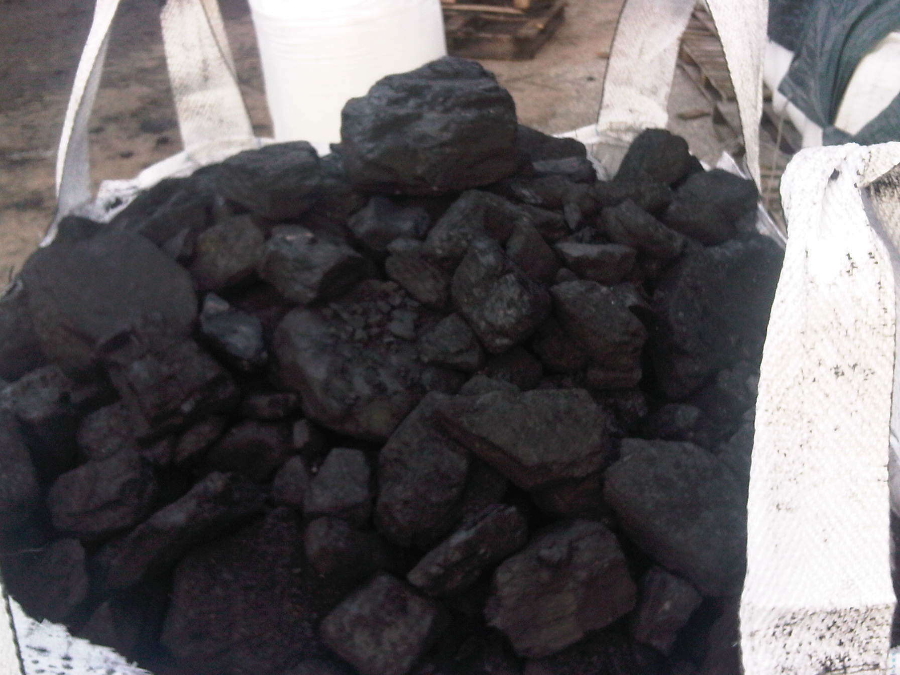 Wypełniony węglem kamiennym worek typu big bag, oferowany przez skład w Lubiczu. Widoczne fragmenty worka i bryły węgla o nieregularnych kształtach.