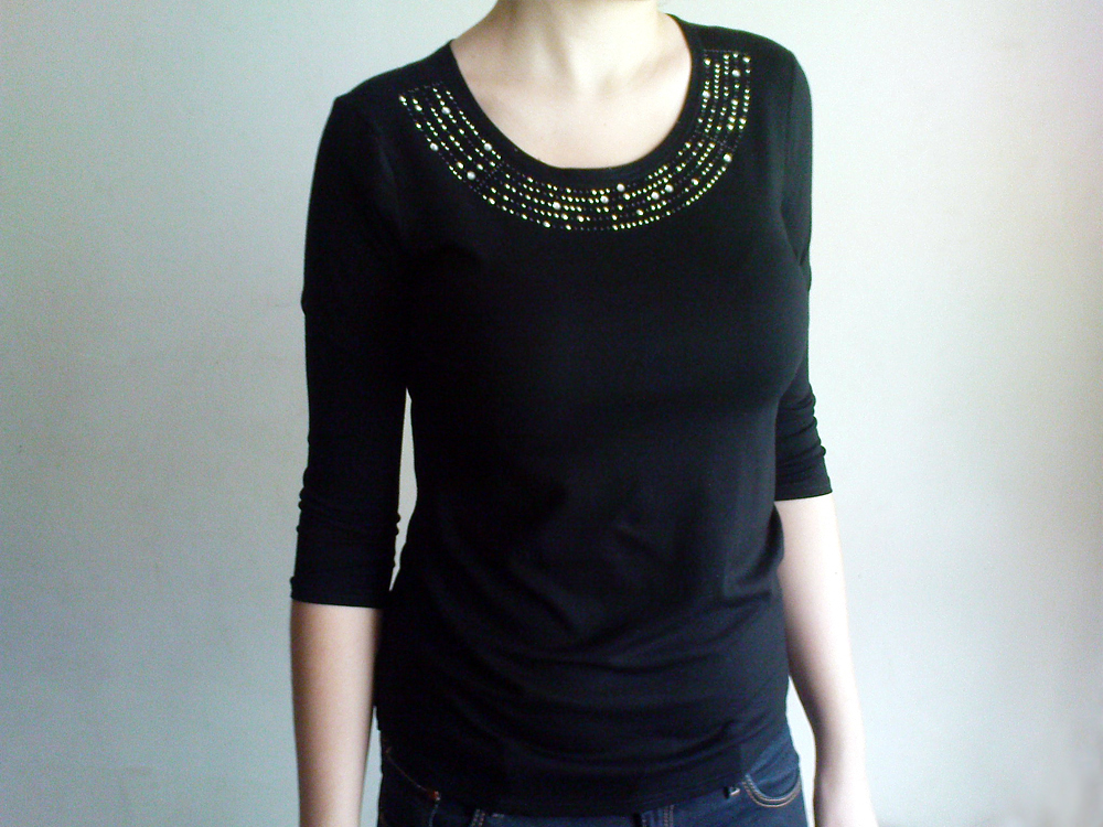 Czarna bluzka damska z rękawem 3/4 i ozdobnym dekoltem z koralików, prezentowana na osobie.