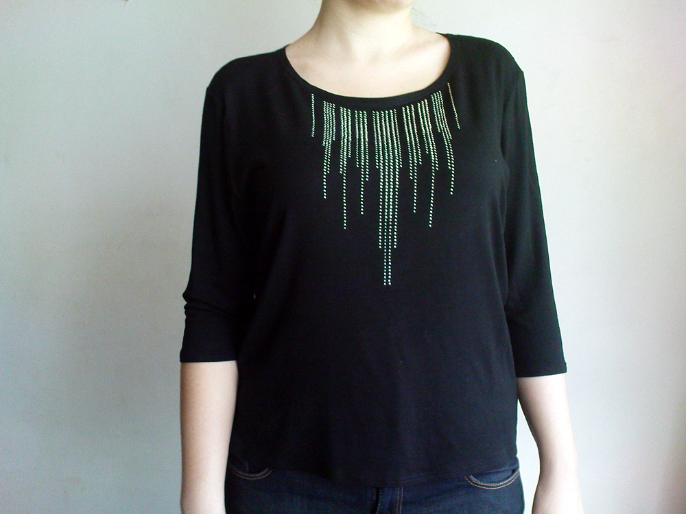 Czarna bluzka damska z dzianiny, z rękawem 3/4 i srebrnym, kaskadowym zdobieniem z dżetów wokół dekoltu, prezentowana na osobie.