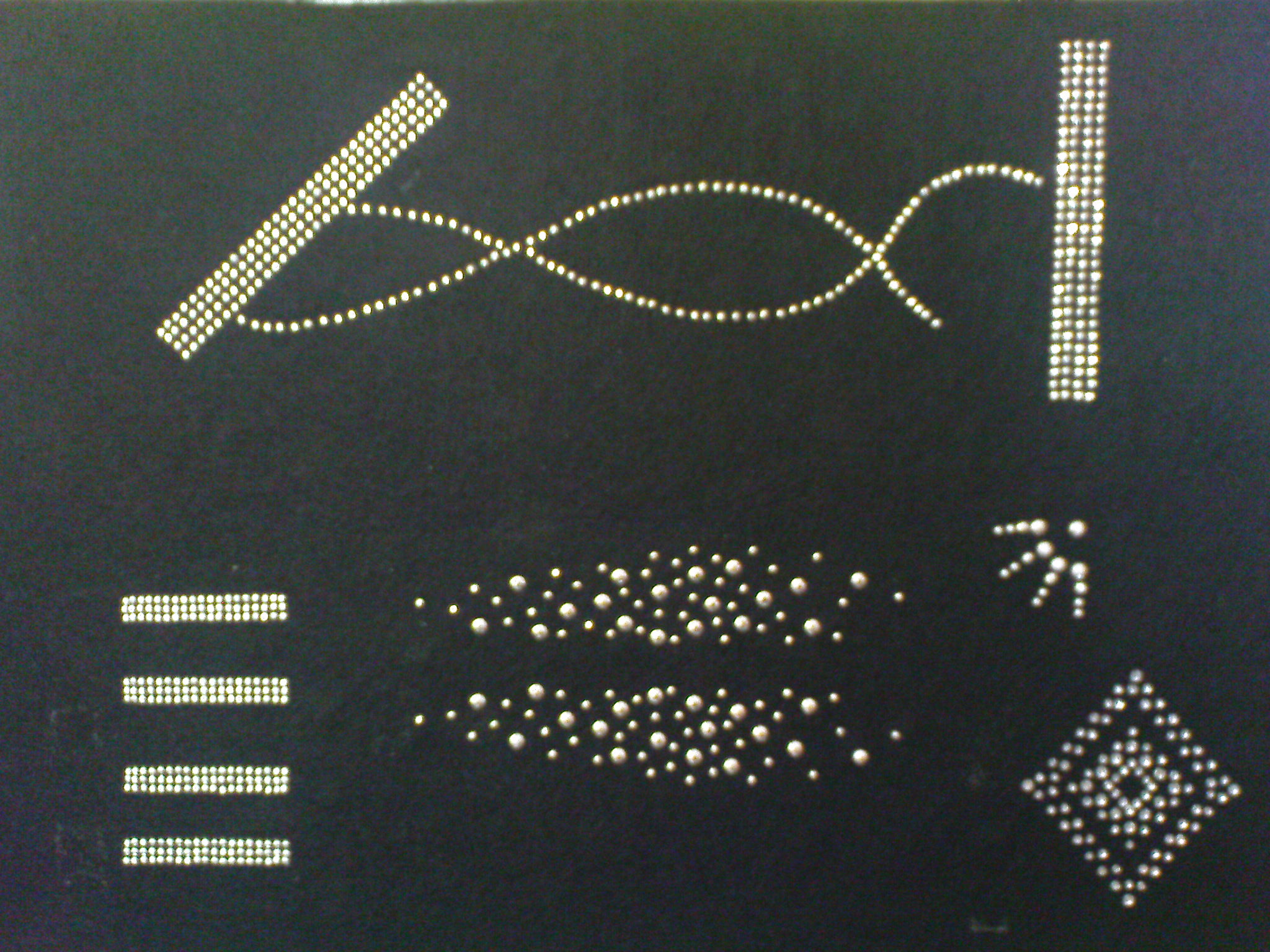 Układ różnych wzorów z dżetów na ciemnym materiale, w tym pasy, linie faliste, rozproszone kropki i kształt rombu.