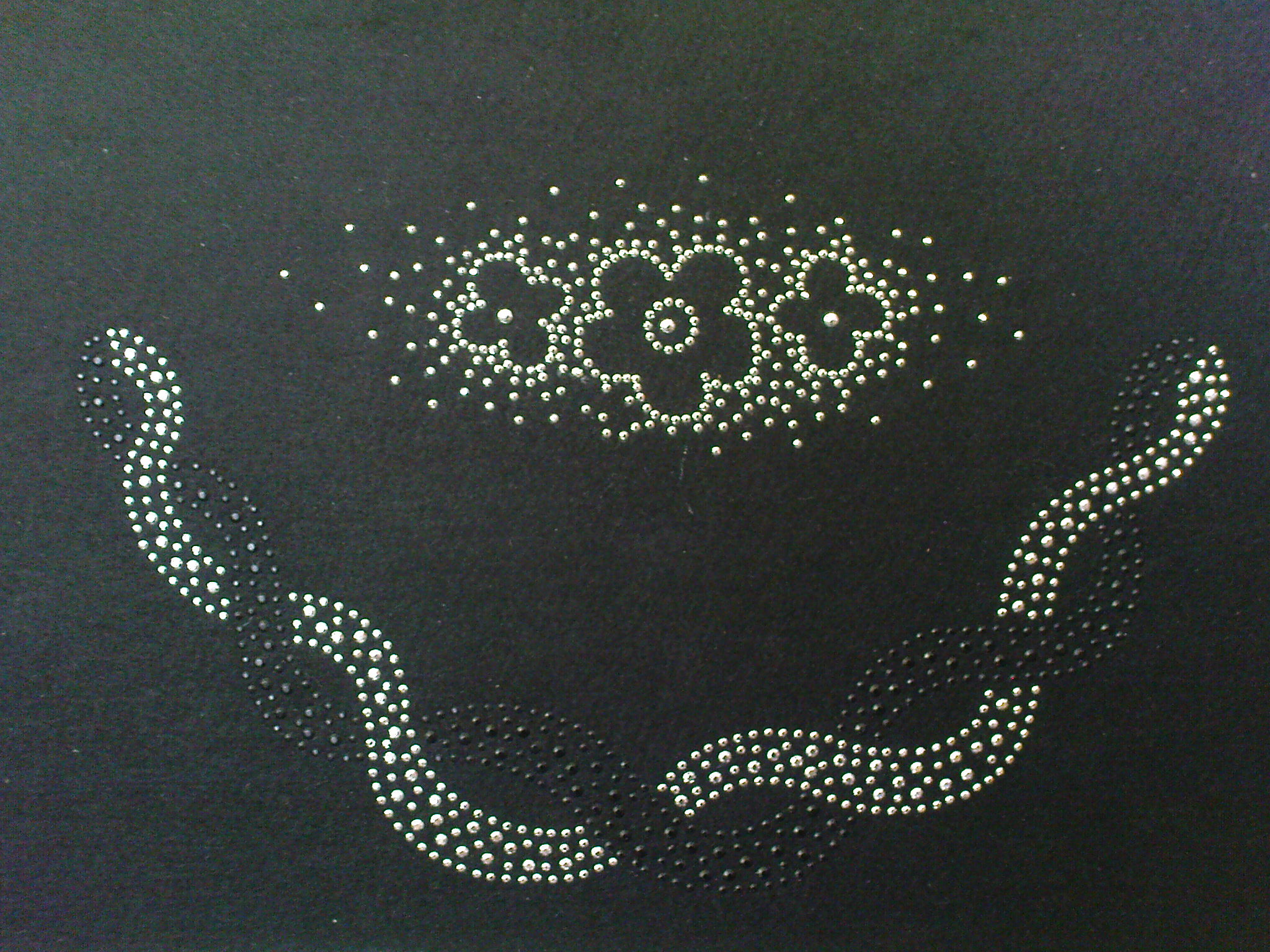 Czarny materiał z aplikacją z dżetów w kształcie kwiatów i falujących linii, wykonaną w Łodzi.