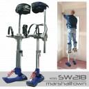 Szczudła malarskie marki Marshalltown SW218 stojące obok pracującego malarza na szczudłach, malującego ścianę w narożniku pokoju, widoczne ślady po taśmie malarskiej na podłodze.