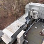 Kompleksowa instalacja wentylacyjna i klimatyzacyjna na dachu budynku, widok z góry, metalowe kanały i jednostki zewnętrzne klimatyzatorów.